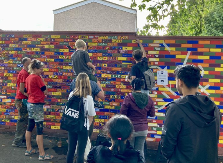 A group of people painting colourful bricks in Newtown, Bristol.