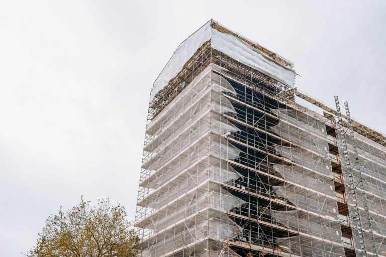 A rectangular tower block covered with scaffolding for fire safety works.