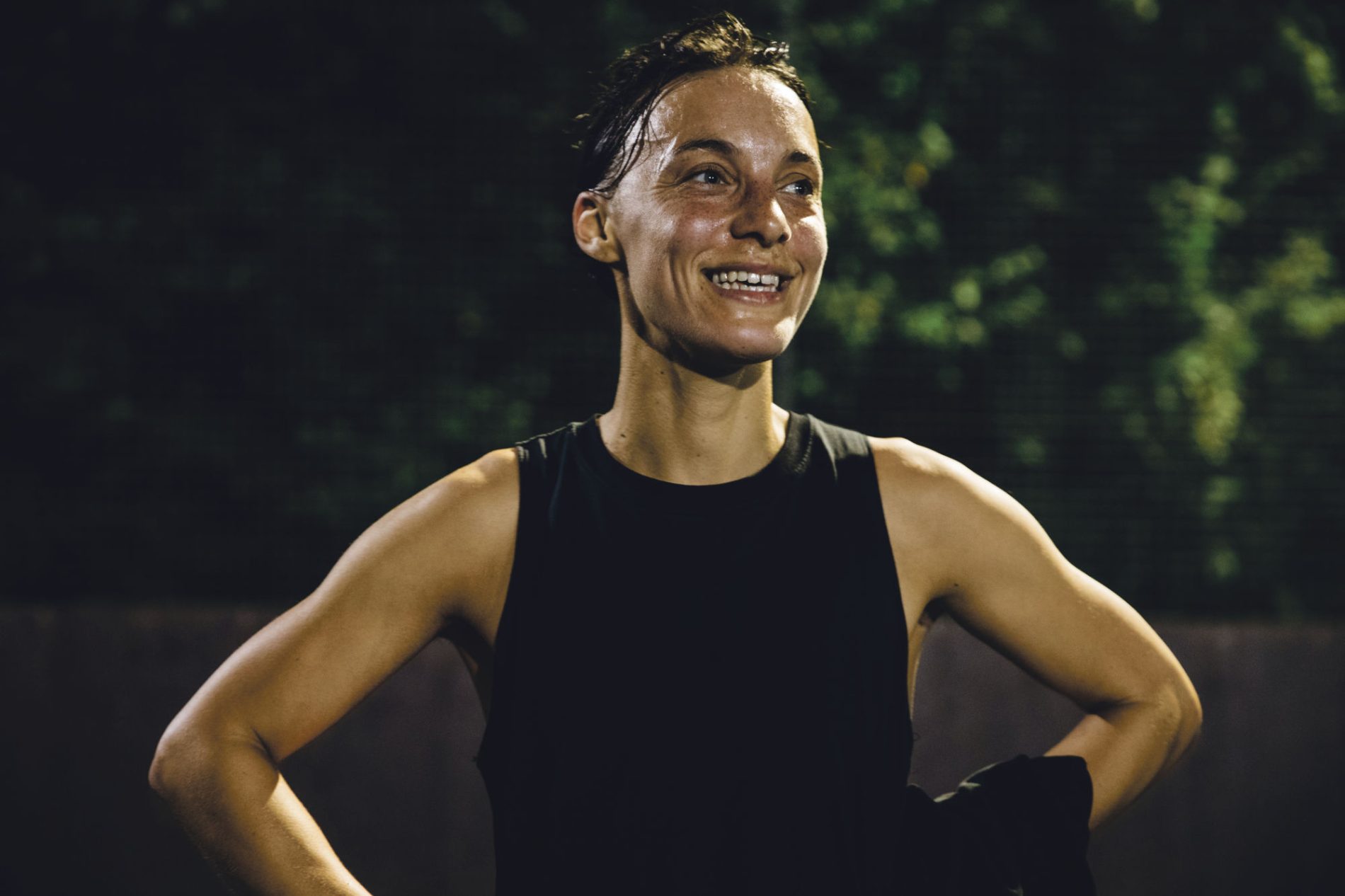 A female football player is smiling during an evening football match.