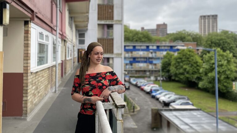 Woman standing on an outside landing of high-rise flats