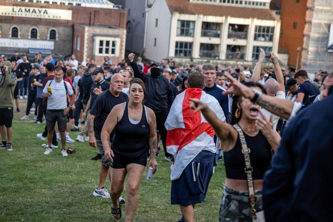 A crowd of protesters shouting in Castle Park, with one man at the front wearing a St George's flag around his shoulders