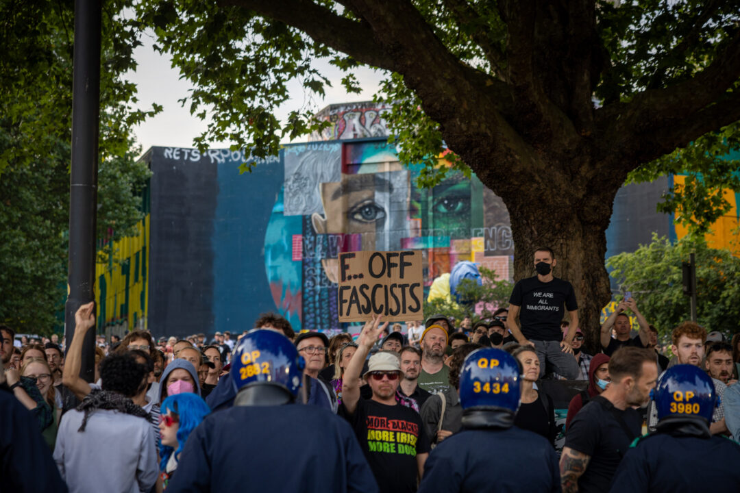 A crowd of counter protesters by Castle Park, with one holding up a placard saying 'Fuck off fascists'