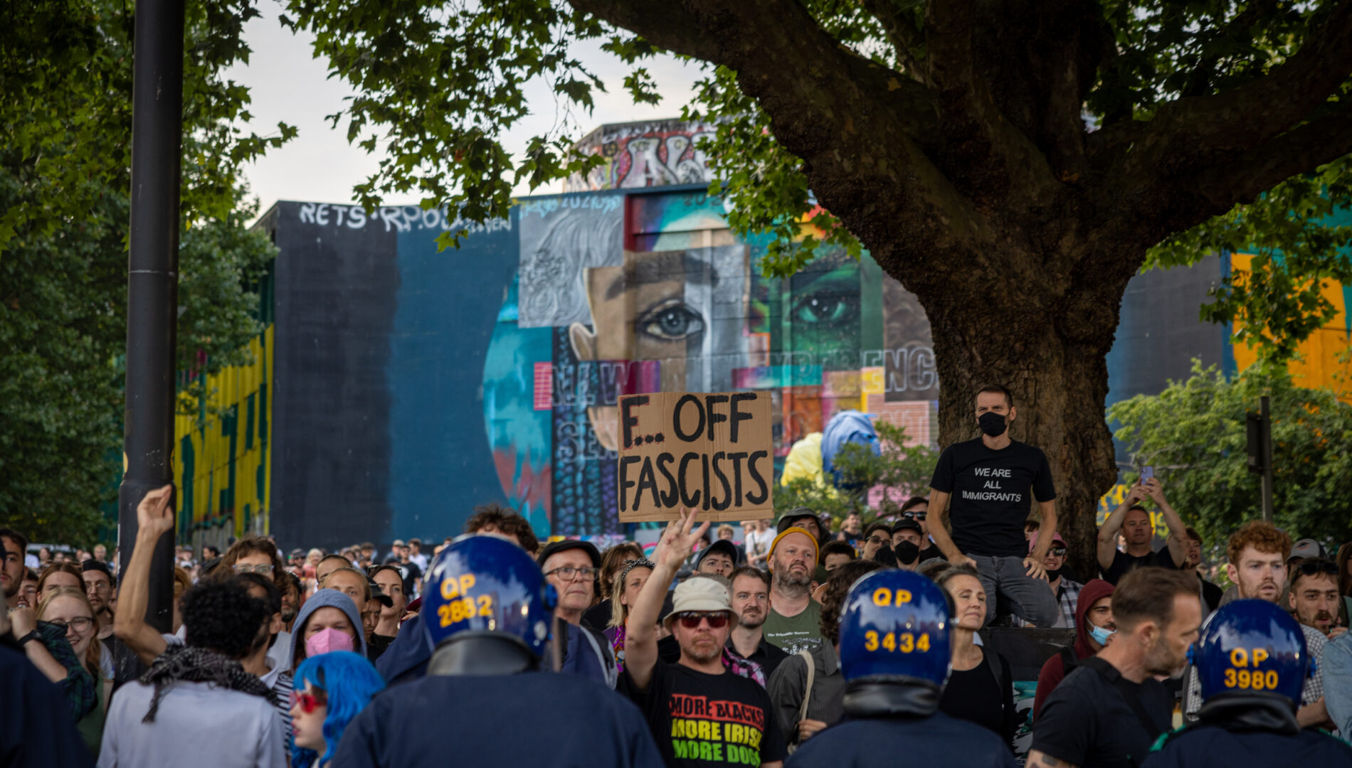 A crowd of counter protesters by Castle Park, with one holding up a placard saying 'Fuck off fascists'