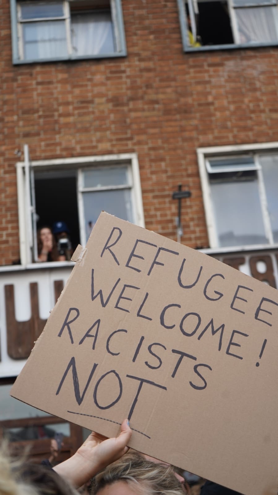 A placard is held aloft saying 'refugee welcome, racists not'