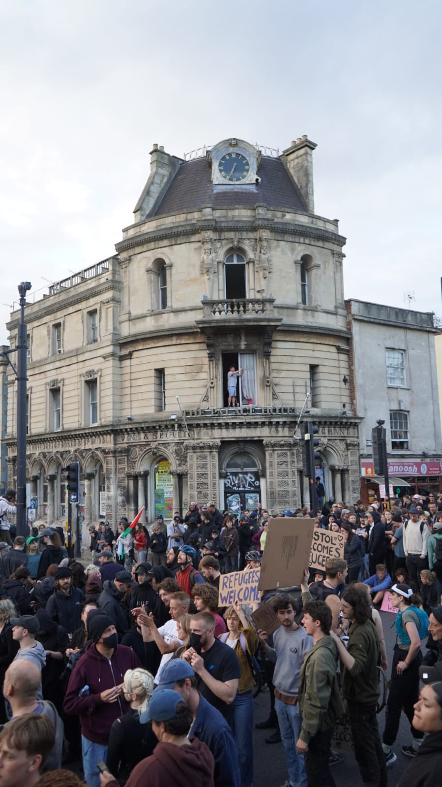 A crowd of protesters stand in the street with placards