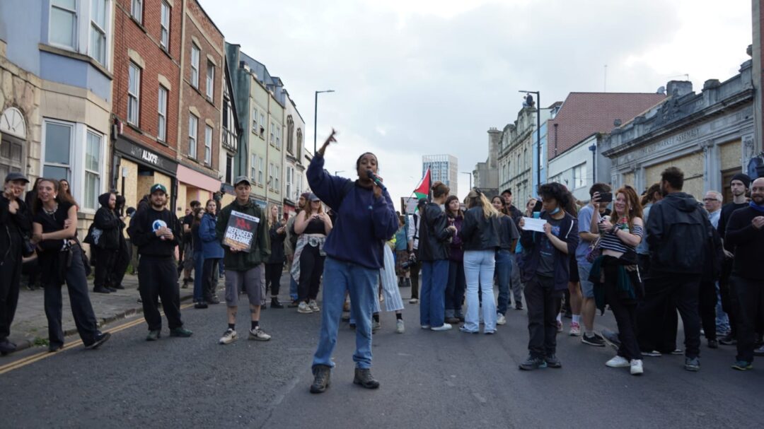 A person gives a speech in front of a crowd of protestors