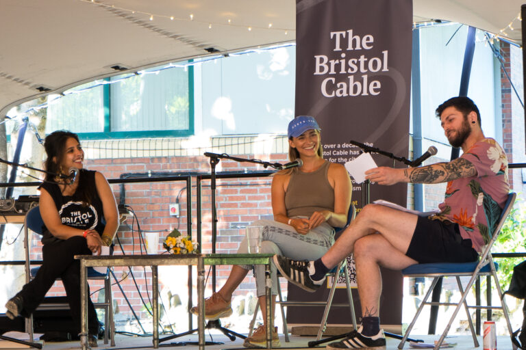 Two journalists sitting on an outdoor stage interview guest speaker Grace Blakeley