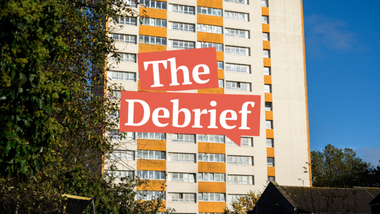 The Barton House high-rise building in Bristol, seen on a sunny day, partially obscured by trees, with a large red banner reading "The Debrief" across the centre.