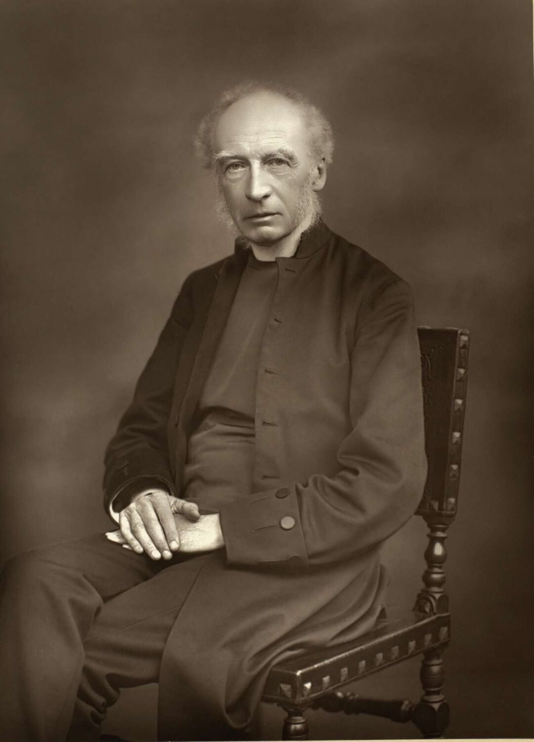 Black and white portrait of a man seated in black clery attire