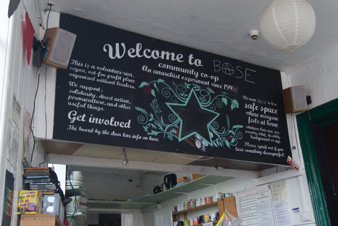 A sign with white chalk lettering on a black board above a kitchen reading 'Welcome to Base'