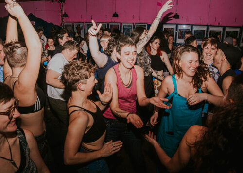 A group of people dancing together in a nightclub with pink walls