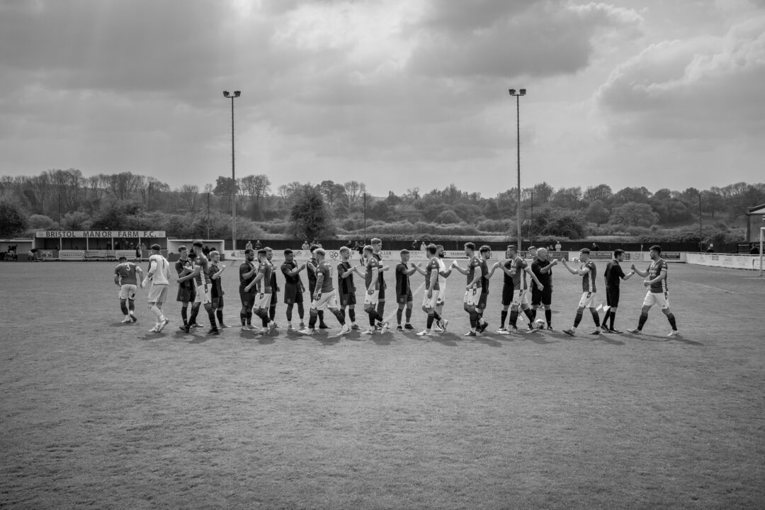 Players from two football teams, walk towards each other in opposite directions to shake hands before a match.