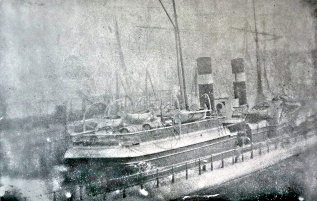 Black and white photograph of an eighteenth-century vessel at port, which two funnels.