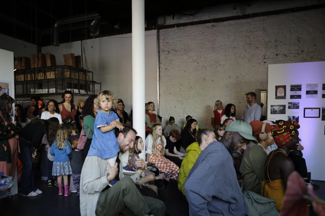 A crowd of people watch a performance in an events space. 
