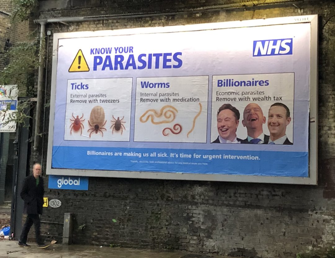 A large blue billboard on a grew brick wall. 