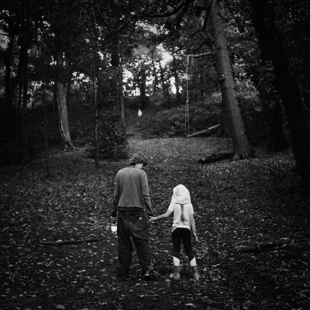 A boy and girl walk through a wooded area. 