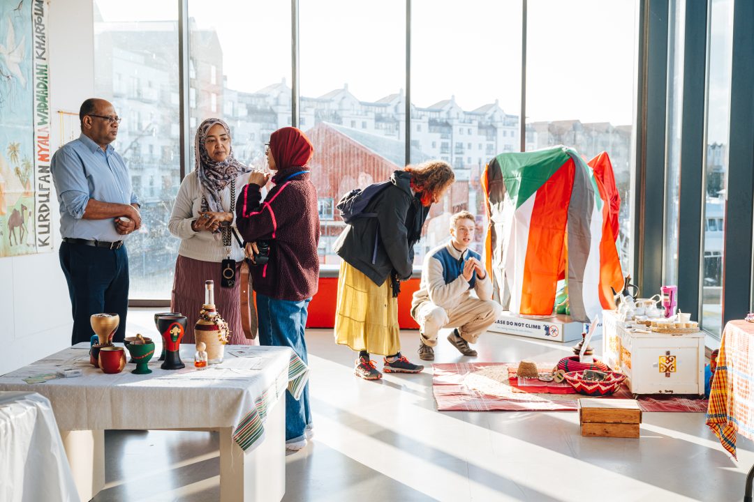 A group of people talk and look at artwork in a galley