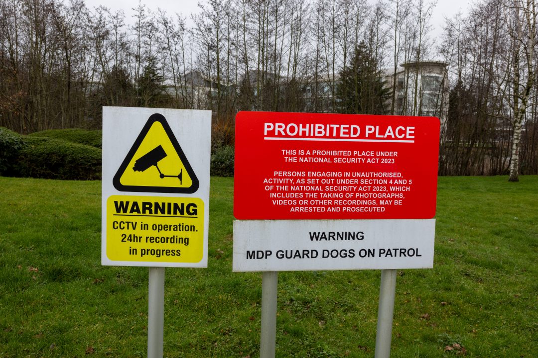 Warning signs on the grass outside an official building. 