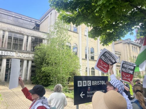 Protesters hold up placards outside a large building
