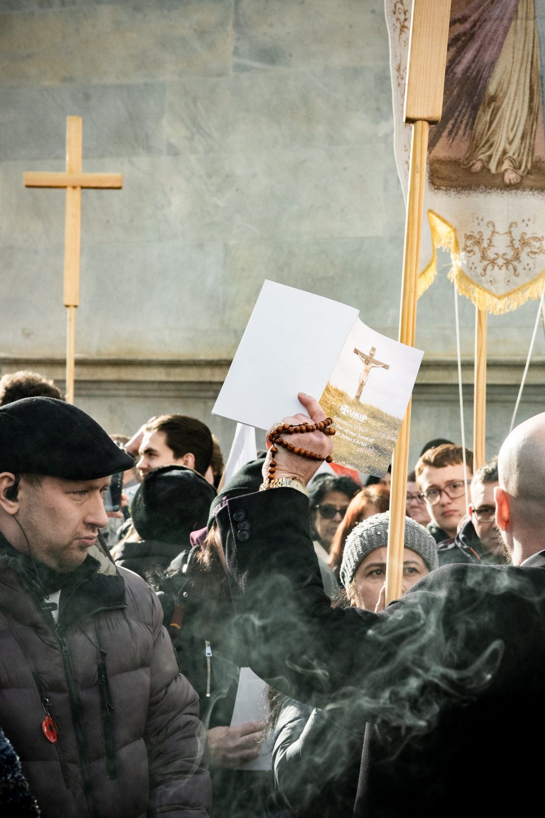 People dressed in dark clothing and holding wooden crosses during a demonstration