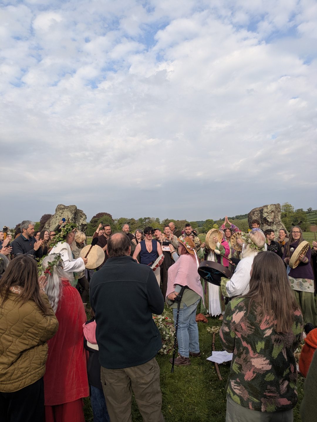 A group of people gather in a field in the middle of a stone circle