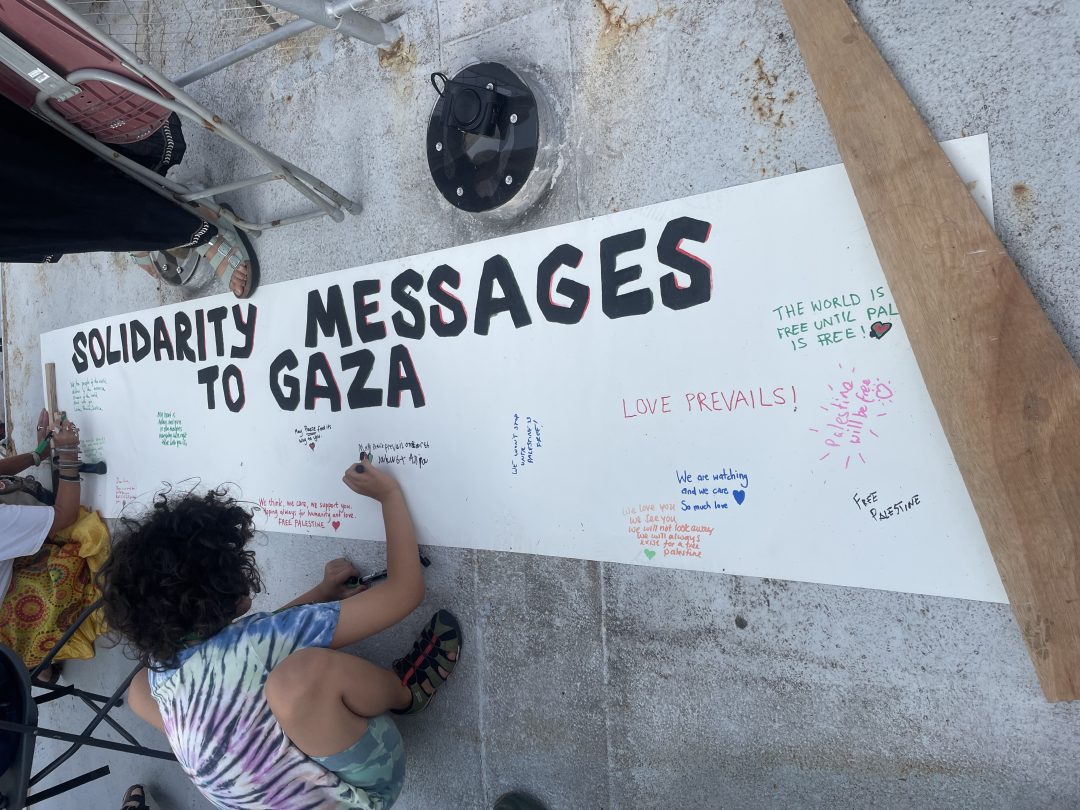 A young woman writes a message on a large white placard