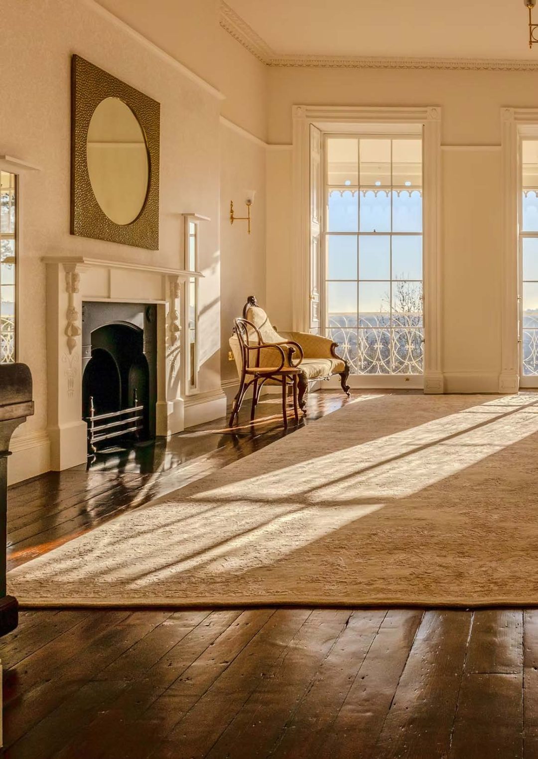 A living room in an upmarket house with light shining through the large windows