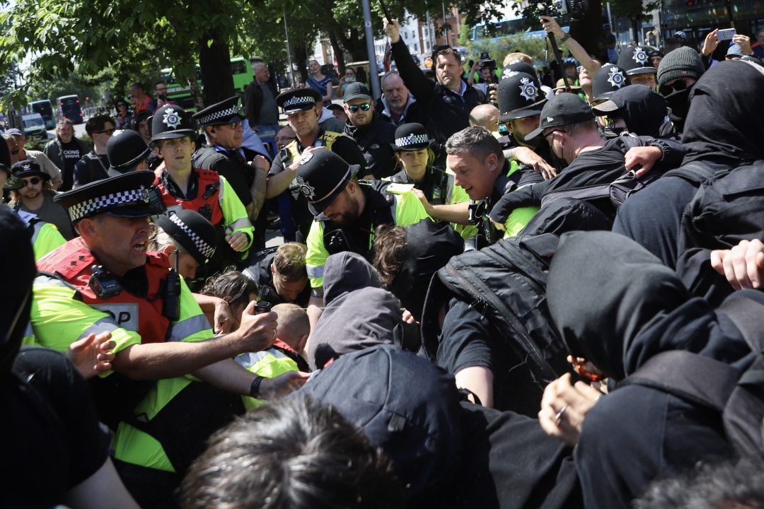 A large group of police officers in an altercation with protesters dressed in black