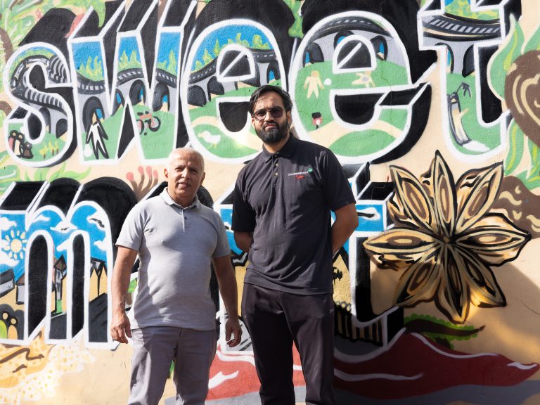 Two men standing in front of a colourful wall
